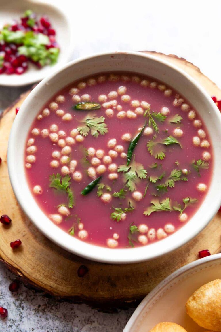 anar pani puri garnished with coriander leaves and boondi and served in a white bowl