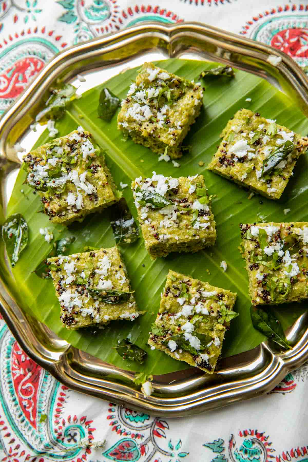 Sprouts dhokla garnished with tempering and served on a leaf platter