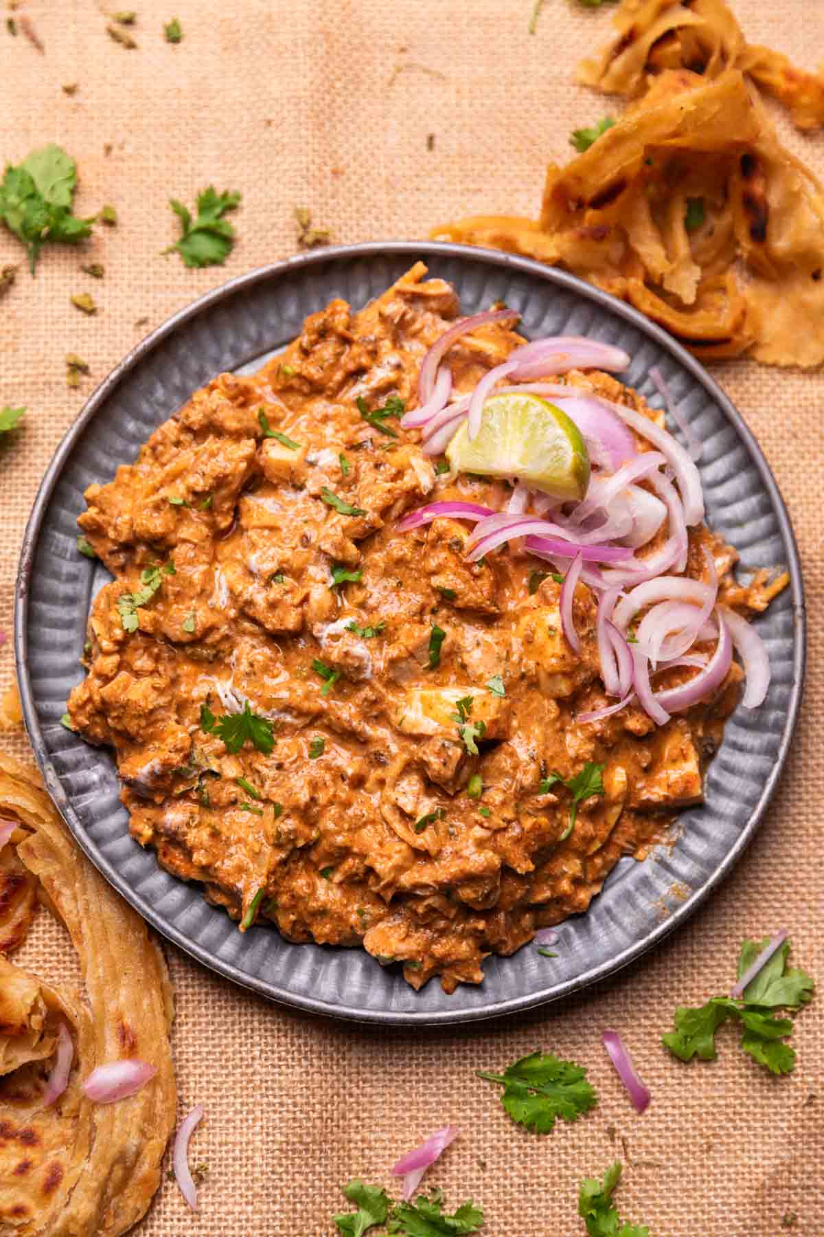 an image of chicken bharta served with sliced ​​onion and lemon wedges